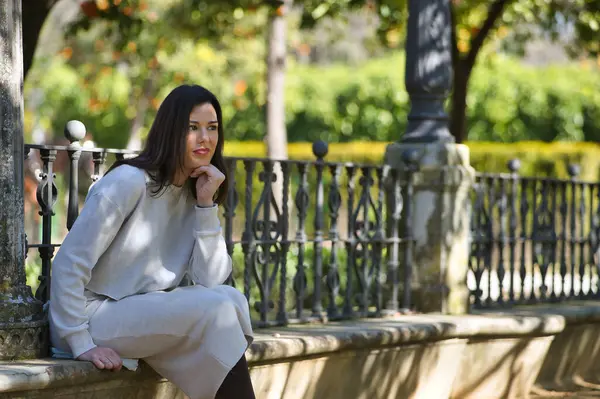 Genç, güzel, siyah saçlı, beyaz elbiseli, düşünceli ve hayalperest bir kadın, eli çenesinde, bir bankta, yalnızlık içinde oturuyor. Güzelliği, modayı, eğilimi, kadınlığı kavra.