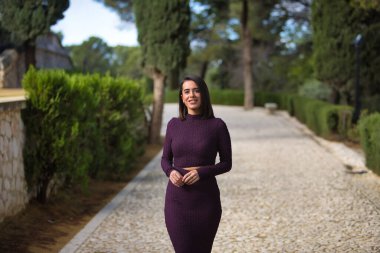 Genç, güzel, esmer, İspanyol bir kadın. Mor bir elbise giyiyor. Gülümsüyor ve mutlu. Güzelliği, modayı, modayı kavra.