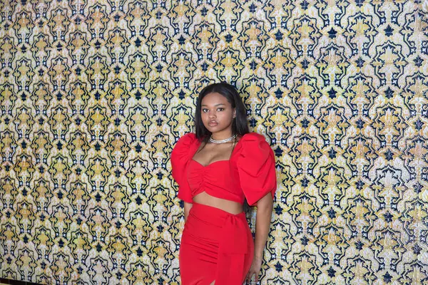 Genç, güzel, kırmızı elbiseli Afrikalı bir kadın. Seville 'de İspanya meydanındaki fayanslı duvara yaslanmış kameraya bakıyor. Moda konsepti, güzellik, moda.