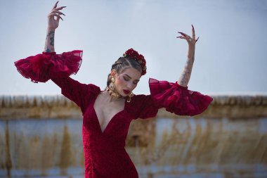 Genç, güzel, sarışın, kırmızı flamenko elbiseli, saçında çiçekler, altın mücevherler, Seville 'de İspanya meydanında fıskiyeli fıskiyelerle flamenko pozları veriyor..