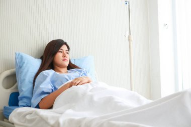 Asyalı kadın hasta, hasta odasındaki yatakta yatarken strese girdi ve endişelendi. Sağlık sigortası kavramı. Hastane sağlık hizmetleri