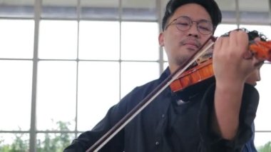 İki Asyalı müzisyen pratik odasında klasik enstrüman, keman ve elektro gitar çalıyor. Canlı müzik ve bando çalma kavramı. Kayıt stüdyosunda müzik çalıyor..
