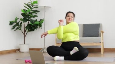 Fat Asian women exercise to lose weight. sitting on the floor watch online video on laptop Exercise according to a fitness trainer. sports concept healthy exercise.