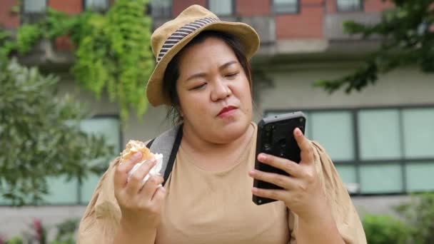 Mulher Gorda Comendo Hambúrguer Segurando Smartphone Conversando Com Amigos Mulher — Vídeo de Stock