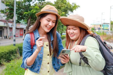 Portrait of two young Asian women traveling on a train. The two were looking at a tourist map on their smartphones. Tourism concept. Traveling by train in Thailand. outdoor adventure travel