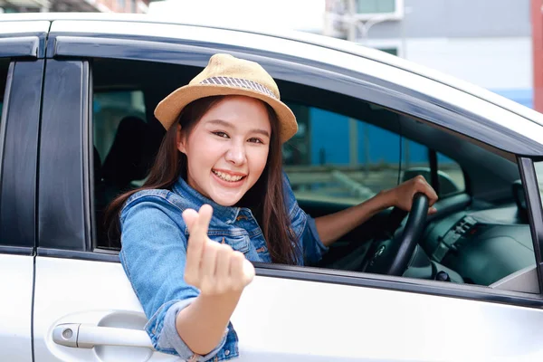 beautiful asian woman driving on a road trip happy smile Raise your hand to make a mini heart. Tourism concept. Transportation, travel by private car. Outdoor adventure travel. car insurance