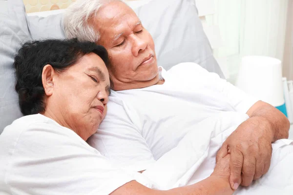 An elderly Asian couple sleeps cuddling in bed in the bedroom. family concept health care, health insurance for seniors