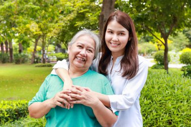 portrait of mother and daughter standing together in the park They both smiled happily. Family concept. Carers for the elderly in retirement age. health care center