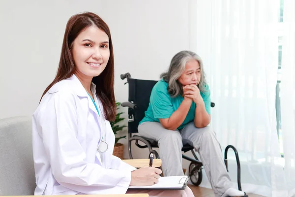 Asian female doctor treats an elderly patient sitting in a wheelchair. Internal Medicine Specialist Take care of the elderly. Hospital medical services
