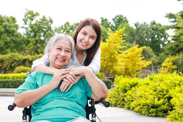 portrait of mother and daughter hugging in the park They both smiled happily. Family concept. Elderly caregivers seated in wheelchairs. health care center