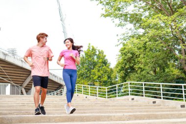 Spor giyimli iki Asyalı genç çift günün erken saatlerinde açık havada koşuyor. Kadın sporcular ve erkek sporcular. Spor konsepti. Sağlıklı bir yaşam tarzı için egzersiz. Boşluğu kopyala