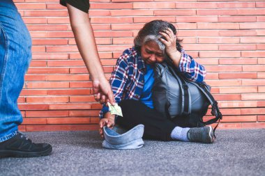 Koridorun ortasında, tuğla duvarın karşısında oturan evsiz yaşlı kadın başkalarından para istiyor. Dilenci!