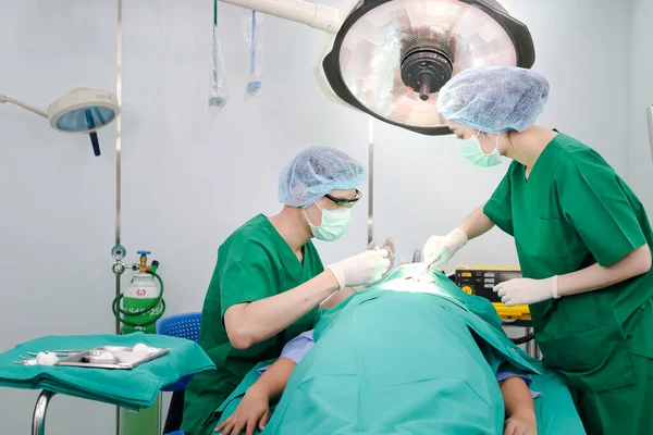 An Asian medical team performs facial surgery on a female patient lying on an operating room bed. Beauty concept. Medical services in hospitals. Surgeon. Emergency accident.