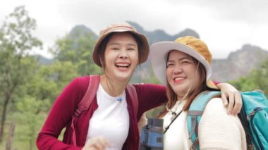 İki Asyalı kadının portresi dağlarda yürüyüş yapan şişman ve sıska gülümseme, neşeli, seyahat etmekten mutlu. Doğa turizmi, seyahat, gezgin, sırt çantası