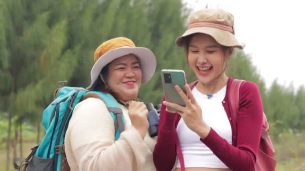 Dos Viajeras Asiáticas Sonriendo Riendo Felizmente Sosteniendo Smartphone Escuchando Música — Vídeo de stock