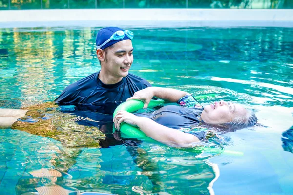 stock image Asian man or physiotherapist helping elderly female patient with hydrotherapy It is a rehabilitation and exercise in the water. physical therapy center