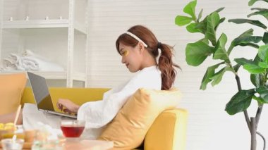 Güzel Asyalı kadın evde spa yapıyor ve ayrıca çalışıyor. Altın ipek bitkisel krem, yüz maskesi, deriyi besler, kolajen ve elastin üretmek için deriyi uyarır. güzellik konsepti
