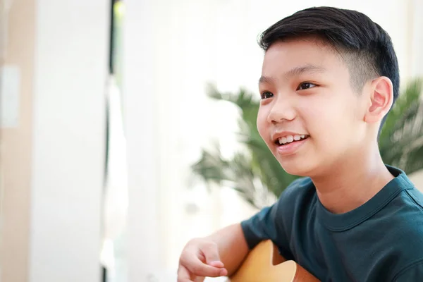 亚洲男孩在家里沙发上弹奏吉他的肖像 音乐概念 儿童学习 — 图库照片