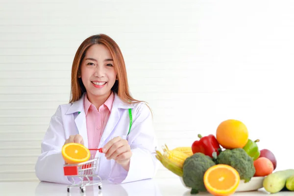 テーブルの上に果物や野菜と白いテーブルの上に座って美しいアジアの栄養士の肖像画 健康的な食のコンセプト — ストック写真