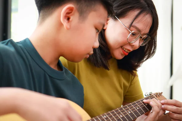 教育观念 学习音乐 妈妈和儿子在家里一起演奏音乐 音乐老师教年轻的亚洲男孩弹吉他 — 图库照片