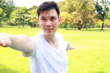 Mutlu gülümseyen Asyalı adam sabah parkta egzersiz yapıyor. Fitness konsepti, sağlık hizmeti