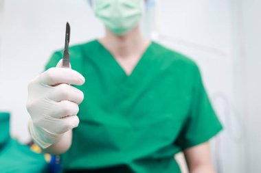 Asyalı cerrah ya da yeşil üniformalı doktor ameliyathanede neşter tutuyor. Estetik ameliyat. Hastanelerde sağlık hizmetleri.