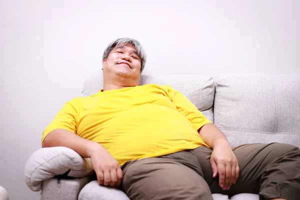 Asian fat man sitting on sofa He smiles happily with life. Concept of losing weight. health care