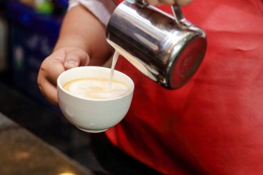 Beretta sıcak kahve yapıyor. Sütü beyaz fayanslı bardağa dök. Kahve dükkanı işi. Girişimcilik.