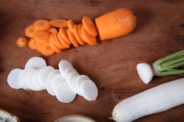 Tahta kesme tahtasına yerleştirilmiş havuç ve turplar. Yemek konsepti. Kimchi, Kore mayalanmış yiyeceği..