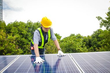 Asyalı teknisyenler güneş pillerini elektrik üretmek ve dağıtmak için kuruyorlar. Enerji teknolojisi konsepti. Boşluğu kopyala