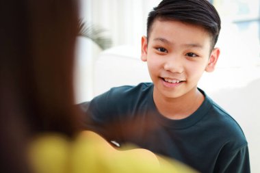 Asyalı çocuk öğretmeniyle akustik gitar çalmayı öğreniyor. Klasik orkestra. müzik eğitimi