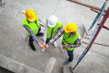 Mühendislerin, mimarların ve müteahhitlerin birbirlerine karşı kollarını açmaları. İnşaat alanında iş birliği yapın. Sanayi konsepti. inşaat teknolojisi