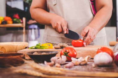 Şişman kız mutfakta yemek pişiriyor pizza için domates doğruyor. Yemek konsepti. Şef yemek yapıyor.