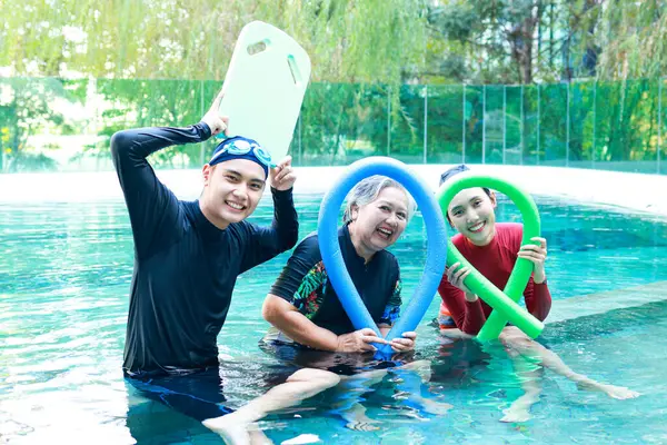 Group portrait of asian people of different ages smiling happily exercising in the water and doing hydrotherapy. It\'s a rejuvenation of the body. Physical therapy center.