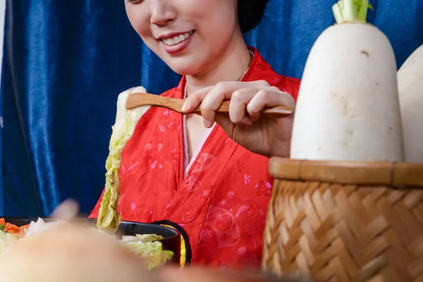 A beautiful Korean woman wearing a beautiful hanbok is making kimchi. Concept of Korean national costume. Fermented food
