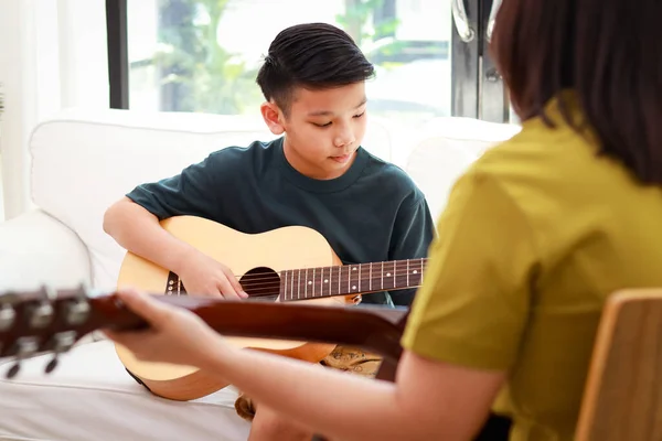 Asian boy learning music playing acoustic guitar with teacher. Classical band. music education