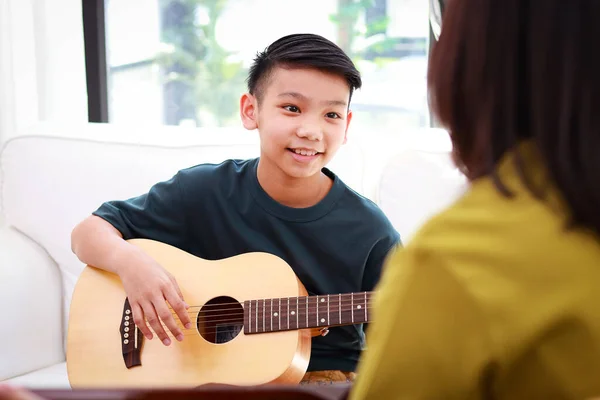 Asian boy learning music playing acoustic guitar with teacher. Classical band. music education