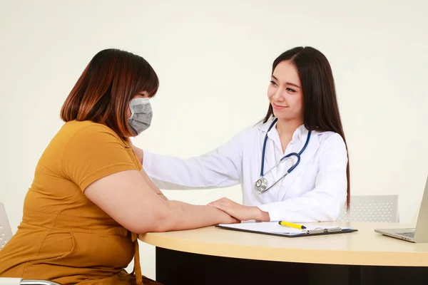 A female doctor examines the health of an obese female patient who wears a surgical mask. Medical services in hospitals.