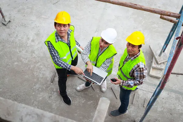 İnşaat alanında ayakta duran ve tartışan bir grup mühendis, mimar ve müteahhit. Sanayi konsepti, inşaat teknolojisi