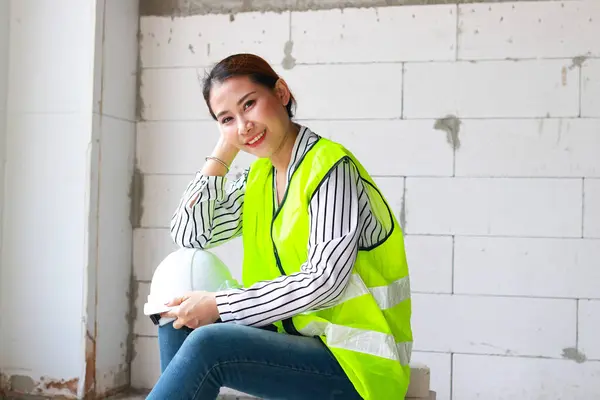 Portrait of an Asian female engineer sitting at a construction site. Construction industry concept. worker health care