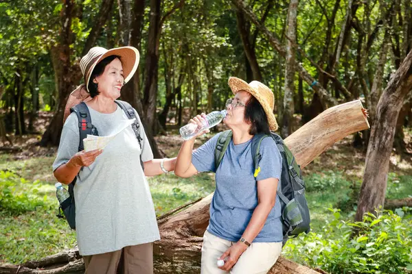两名亚洲老年妇女徒步旅行自然喝水解渴 退休旅行 图库图片
