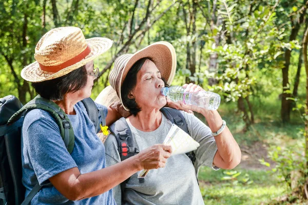 两名亚洲老年妇女徒步旅行自然喝水解渴 退休旅行 图库图片