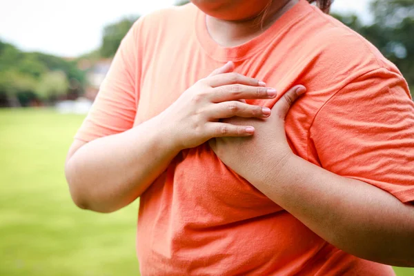 Fat woman exercising outdoors Have heart pain. Health care for obese people. Heart disease.