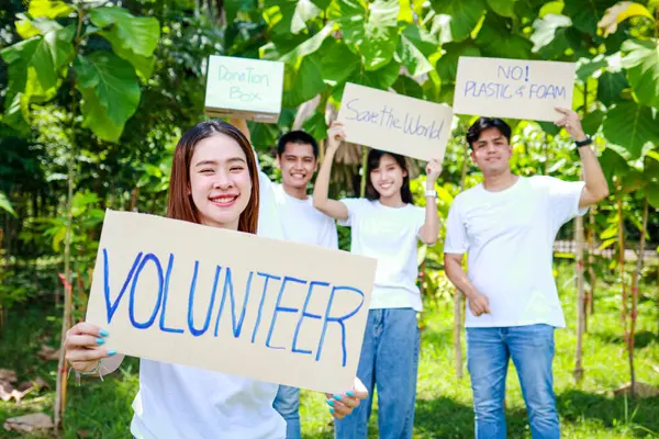 亚洲青年志愿者小组举着支持自然和环境的标志 社会志愿者概念 世界环境日 免版税图库图片