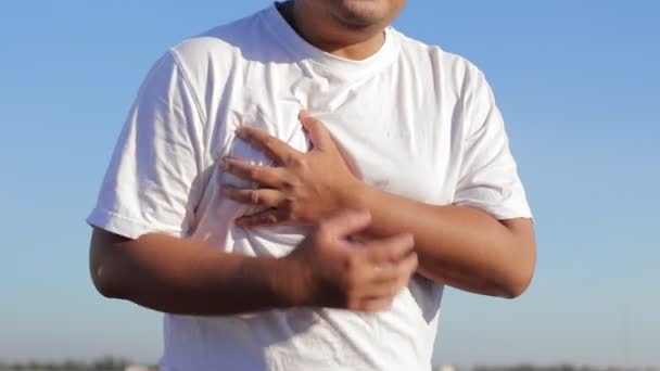 白いシャツを着ている太った男は 左胸に手を置く 彼はジョギング後に心臓の痛みを経験した スポーツコンセプト 体重減少のための運動 — ストック動画