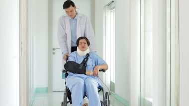 Yumuşak yakalı şişman kadın hastayla ilgilenen Asyalı doktor tekerlekli sandalyede oturuyor. Hastanede tıbbi hizmet kavramı