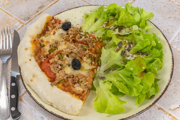 slice of pizza with tuna and salad close up