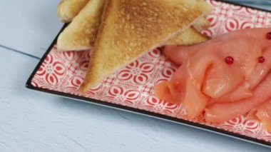 Bir tabak füme somon ve tost yakın.