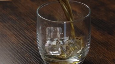 whiskey served in a glass with ice cubes on a table