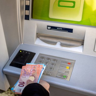 person, close-up, withdrawing money from an ATM